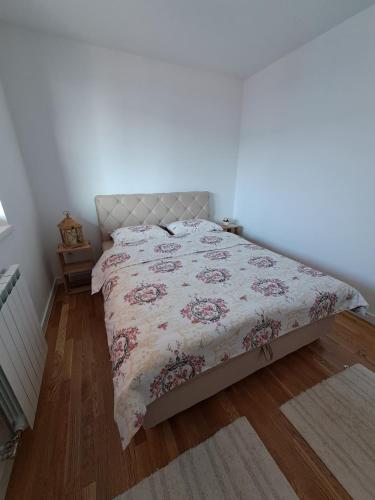 a bedroom with a bed with a floral bedspread at Stan na dan Iv in Lukavica