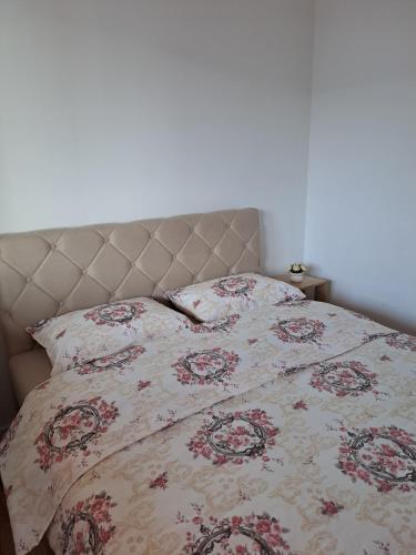 a bed with a flowered comforter and a pillow at Stan na dan Iv in Lukavica