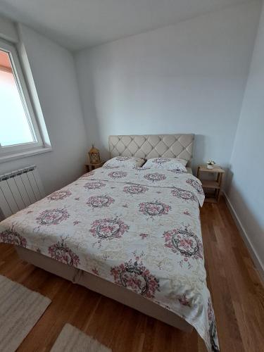 a bedroom with a bed with a floral bedspread at Stan na dan Iv in Lukavica