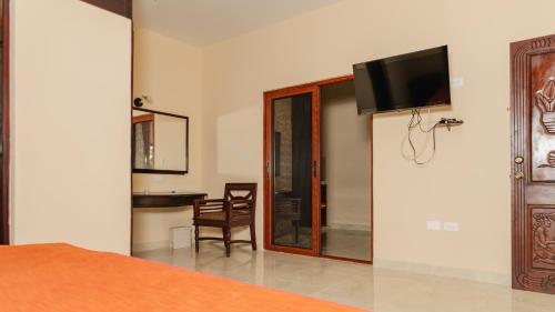a bedroom with a tv on the wall and a table at Hotel Nojoch che in Cobá