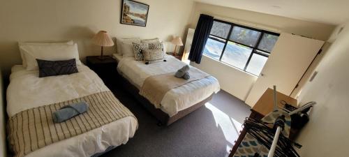 1 dormitorio con 2 camas y ventana en Atarau Grove Holiday House, en Paraparaumu
