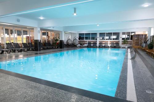a large swimming pool with blue water in a building at PJ Motel Pilot in Cazin