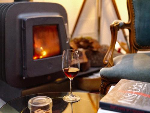 a glass of wine sitting on a table with a fireplace at toctoctoc lisboa in Lisbon