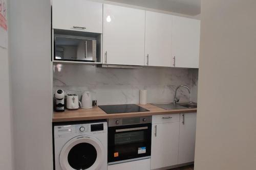 a kitchen with white cabinets and a washing machine at Appart Cosy Auber Porte de Paris in Aubervilliers