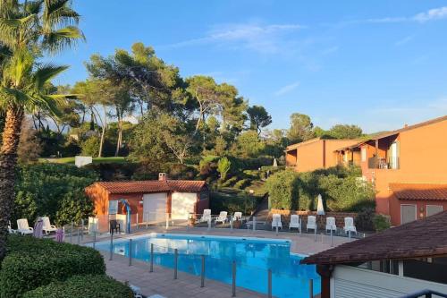 a swimming pool in a yard with chairs and a building at Studio meublé en face du golf côté piscine in Mouans-Sartoux