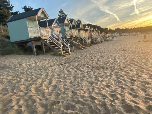 a row of beach huts on a sandy beach at Jolly Sailors Retreat in Wells next the Sea