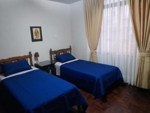 1 Schlafzimmer mit 2 Betten mit blauer Bettwäsche und einem Fenster in der Unterkunft Casa Navarra in Lima