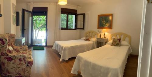 una sala de estar con 2 camas y una silla en Casa rural El Olivo en Aracena