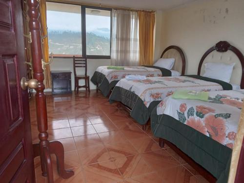 a room with three beds and a window at Hotel International Prestige in Ambato