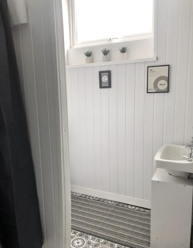 a white bathroom with a sink and a window at 1 Richmond Tce, Flat 2 in Swansea