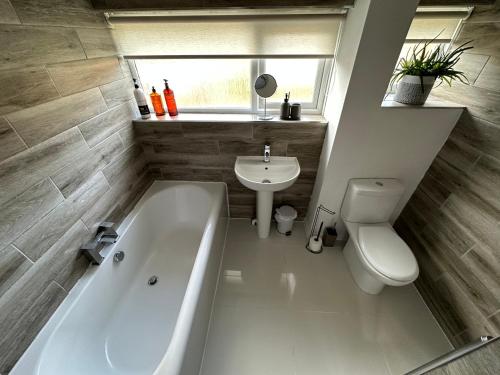 a bathroom with a tub and a toilet and a sink at Spacious and stylish 3-bed home ideal for families in Stockton-on-Tees