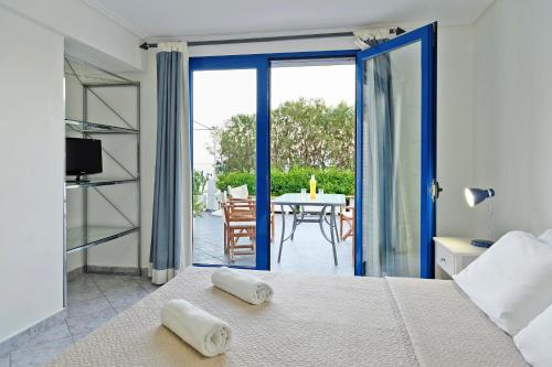 1 dormitorio con 1 cama y balcón con mesa en Aliki Studios, en Paralia Agias Foteinis