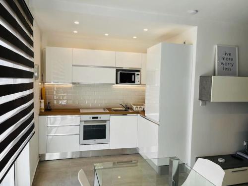 cocina con armarios blancos y mesa de cristal en Sliema, Apt7, Stylish 2 Bedroom Apartment with Parking en Sliema