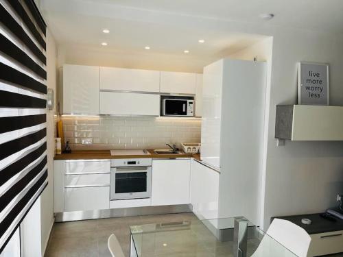 a kitchen with white cabinets and a glass table at Sliema, Apt7, Stylish 2 Bedroom Apartment with Parking in Sliema