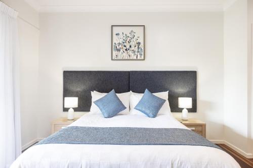 um quarto com uma cama grande e almofadas azuis em Camelot Boutique Accommodation em Mount Tamborine