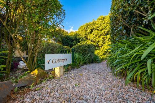 a sign for a garden with a sign that reads cottages at Camelot Boutique Accommodation in Mount Tamborine