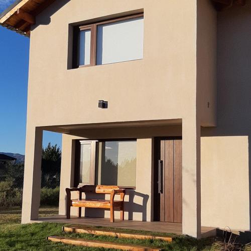 a house with a table and a bench on the porch at Jardín de Estepa in Dina Huapi