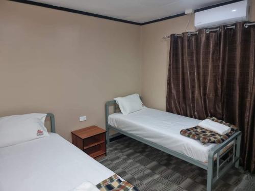 a room with two beds and a window at Al - Minhaj Service Apartments in Nadi