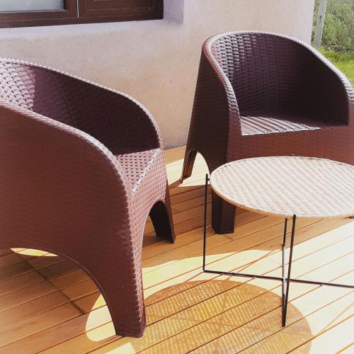 two wicker chairs and a table on a porch at Jardín de Estepa in Dina Huapi