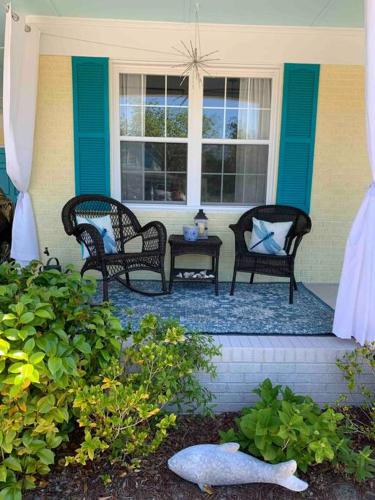 a porch with three chairs and a table and a window at Downtown- Sunshine Cottage and Golf Cart in Southport
