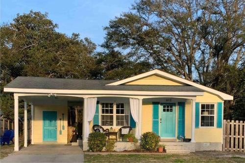 a small yellow and blue house with a porch at Downtown- Sunshine Cottage and Golf Cart in Southport