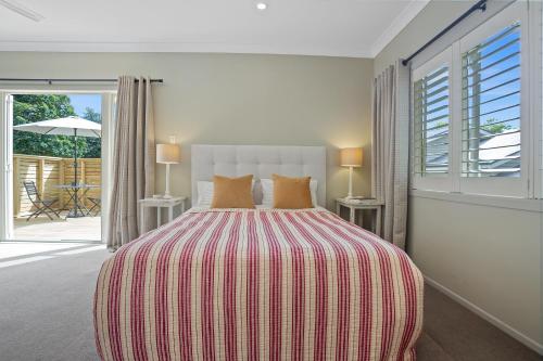 een slaapkamer met een bed met een rode en witte gestreepte deken bij Titoki Cottage in Tahawai