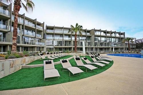 a row of lounge chairs on a lawn in front of a building at Resort Two Bedroom 263 in Torquay