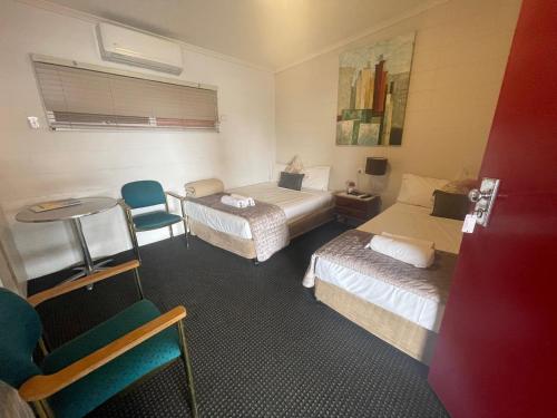 een kamer met 2 bedden en een tafel en stoelen bij Dalby Hotel Motel in Dalby