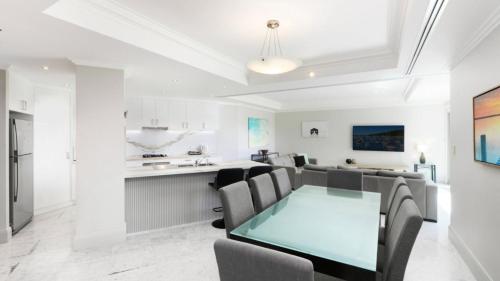 Un comedor y una cocina con una mesa de cristal y sillas. en Unit 48 - 3 Bed Ocean View, en Terrigal