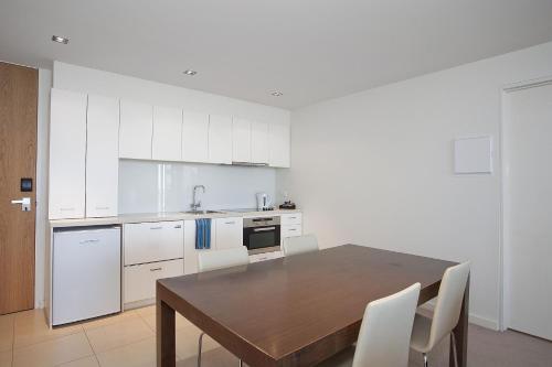 a kitchen with a wooden table and white cabinets at Resort Two Bedroom 257 in Torquay