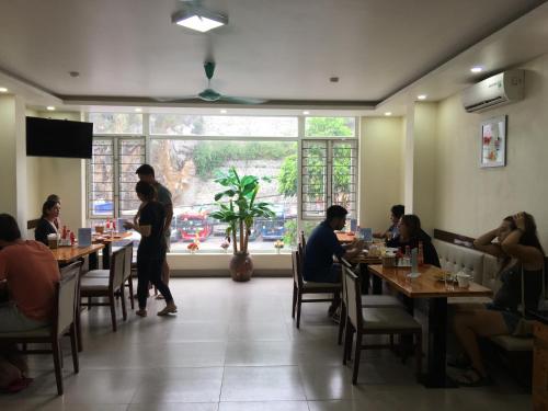 a group of people sitting at tables in a restaurant at CAT BA ROSALIA HOTEL in Cat Ba