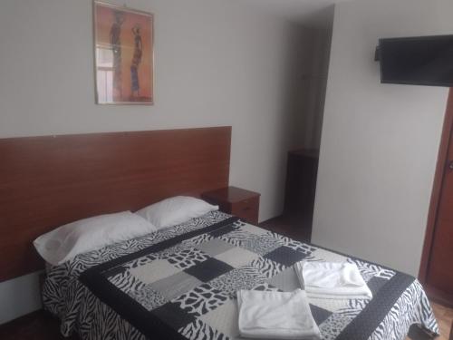 a bedroom with a bed with a black and white blanket at Casa de Isabel in Arequipa
