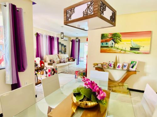a living room with a glass table and purple curtains at Villa Paradise in Brazil - Praia de Guaratiba Prado-BA in Prado