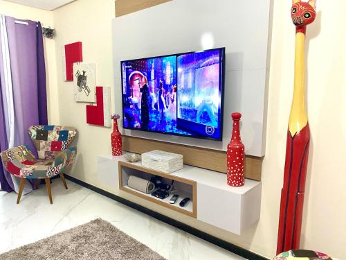 a living room with a flat screen tv on a wall at Villa Paradise in Brazil - Praia de Guaratiba Prado-BA in Prado