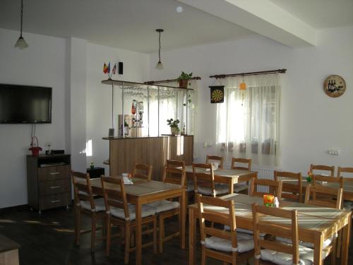 a dining room with tables and chairs and a flat screen tv at Casa Altfel in Malaia