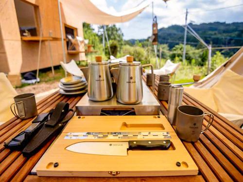 a cutting board on a table with pots and pans at 和心村ー古民家とグランピングと自然森山川海 in Minato