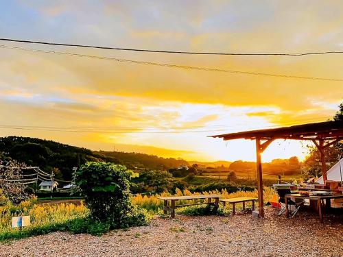a picnic table with a sunset in the background at 和心村ー古民家とグランピングと自然森山川海 in Minato