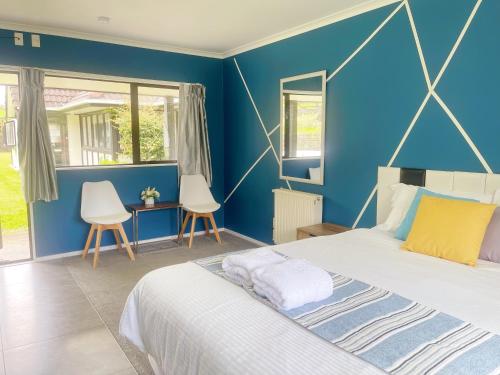 a blue bedroom with a bed and two chairs at Westminster Mount View Unit 1 in Rotorua