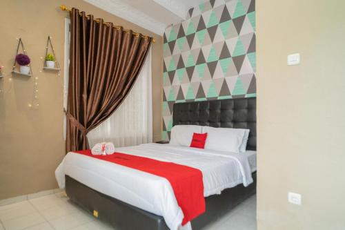a bedroom with a large bed with a red blanket at RedDoorz near Taman Safari 2 in Bogor