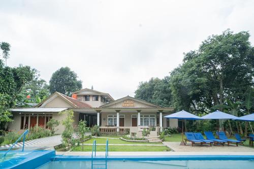 a house with a swimming pool and blue chairs at RedDoorz near Taman Safari 2 in Bogor
