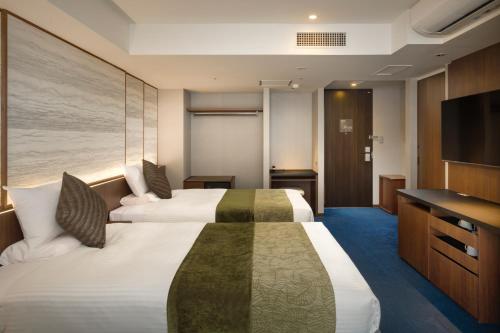 a hotel room with two beds and a television at Tateshina Grand Hotel Takinoyu in Chino