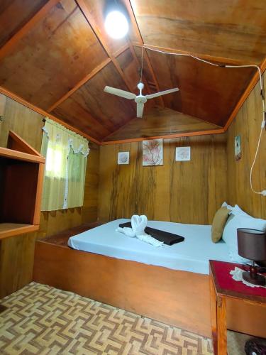 a bed in a wooden room with a ceiling at Adrianas Place in Panglao