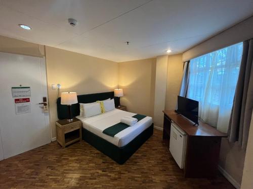 a hotel room with a bed and a television at Coco Grande Hotel in Dumaguete