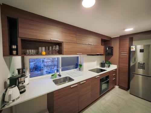 a kitchen with wooden cabinets and a laptop on a counter at Cómodo departamento familiar a pasos de la playa in Viña del Mar