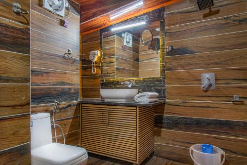 a bathroom with wooden walls and a toilet and a sink at The BlackPearl Hillcrest in Kasauli