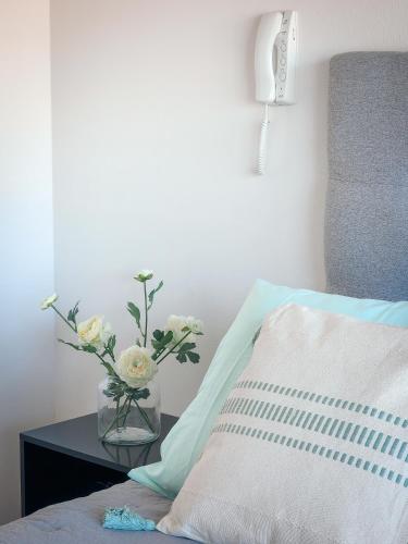a vase of flowers on a table next to a bed at Cómodo departamento familiar a pasos de la playa in Viña del Mar
