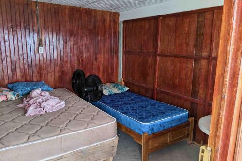 a room with two beds in a room with wooden walls at Private Room in San Blas in Wagsalatupo Grande