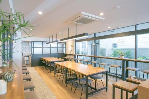 un restaurante con mesas y sillas de madera y ventanas en Hotel Gee Haive, en Mishima