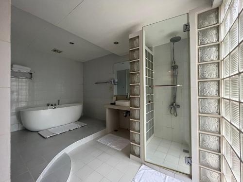 een badkamer met een bad, een douche en een wastafel bij Coco Grande Hotel in Dumaguete