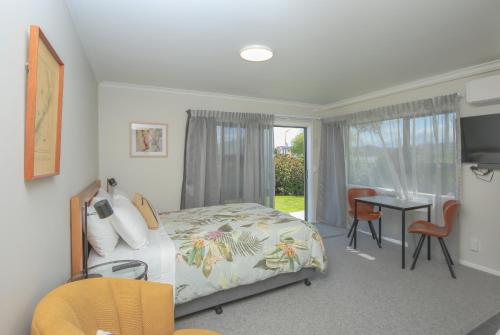 a bedroom with a bed and a desk and a window at Smith House in Whanganui